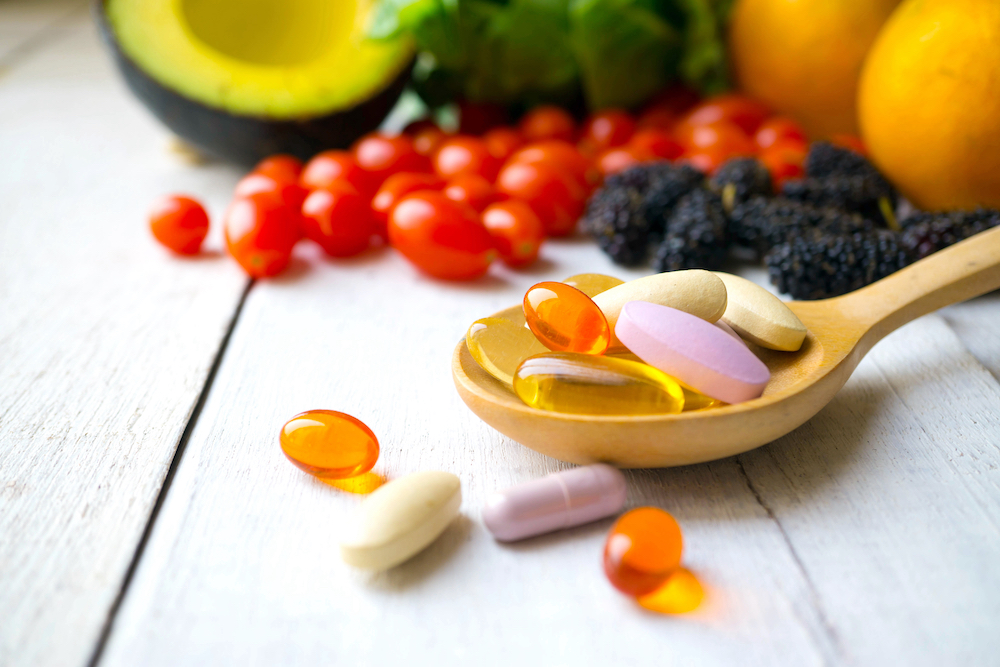 Vitamins and minerals laid out on a table with a wooden spoon