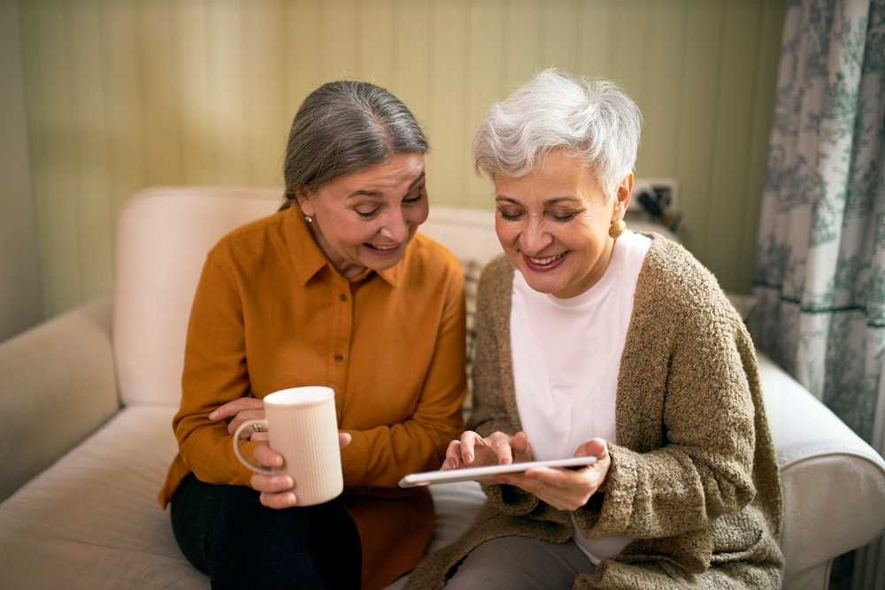 Two senior women play a game together on a tablet