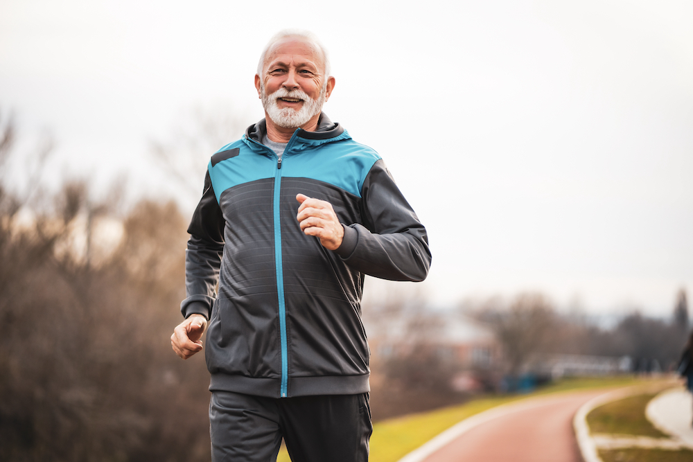 A senior man jogging outdoors in a park