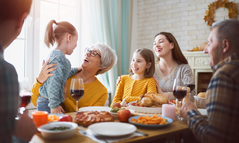 A senior woman and her family enjoy Thanksgiving together eating at a table