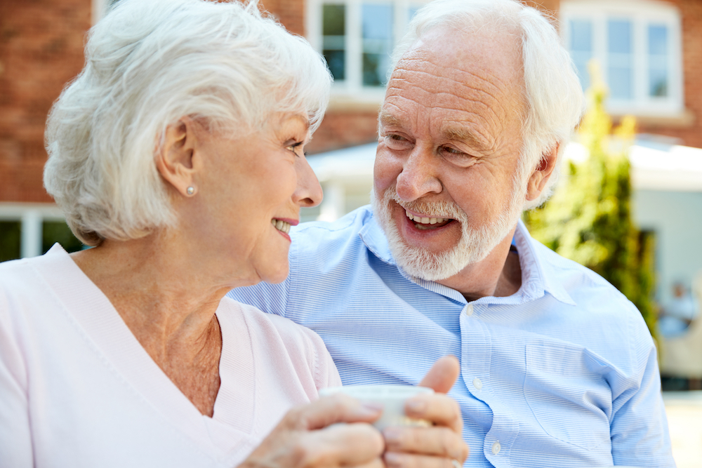 A senior couple sits outside to drink their coffee at the independent senior living in Madison Heights