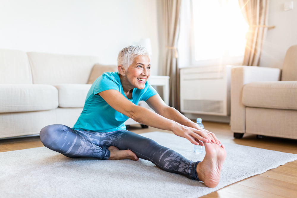 A senior woman stretching and doing yoga indoors