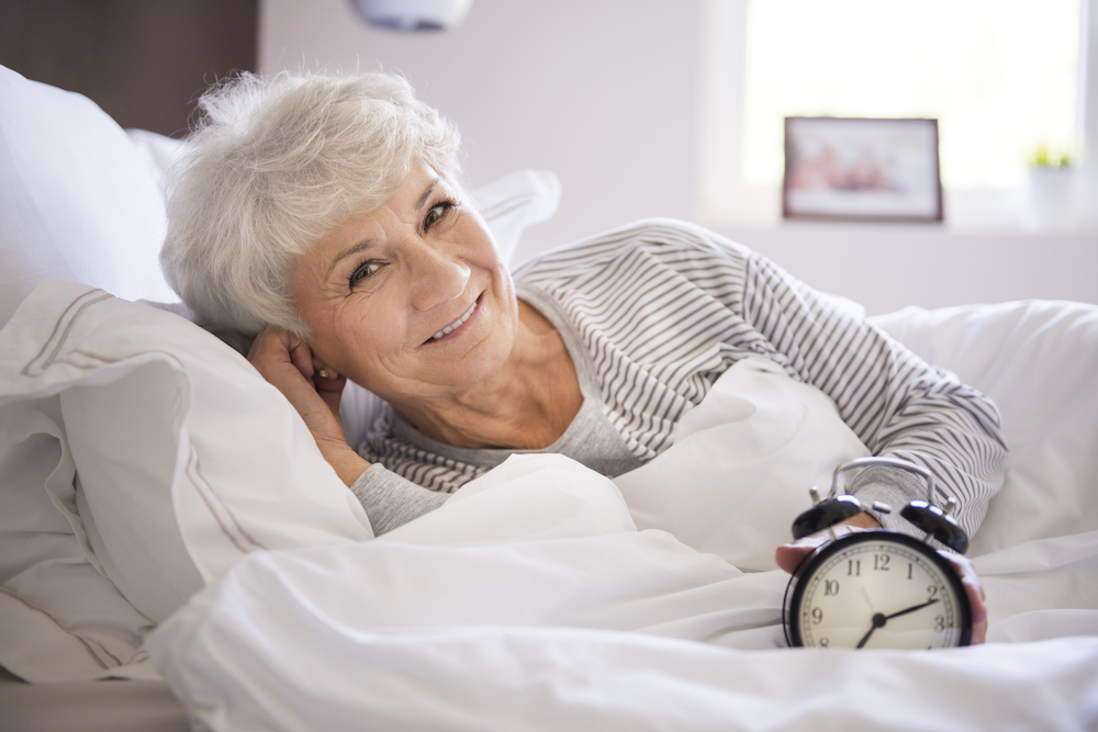 A senior woman waking up in her bed in the morning