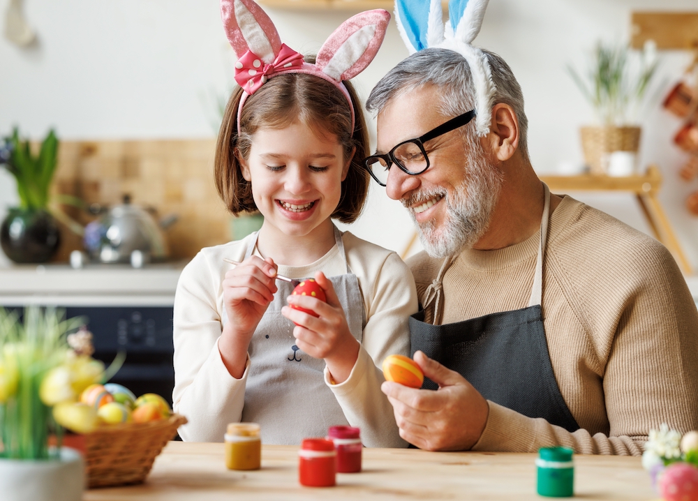 A senior man painting Easter eggs with his granddaughter at the Madison Heights senior apartments