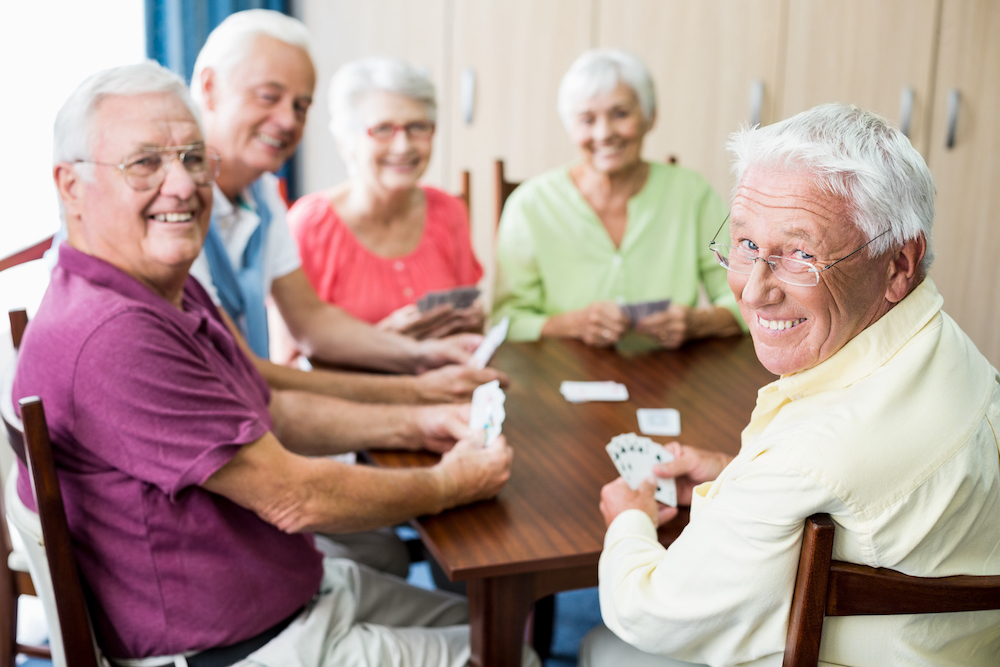 A group of friends enjoy playing a card game together at the best senior independent living in Michigan