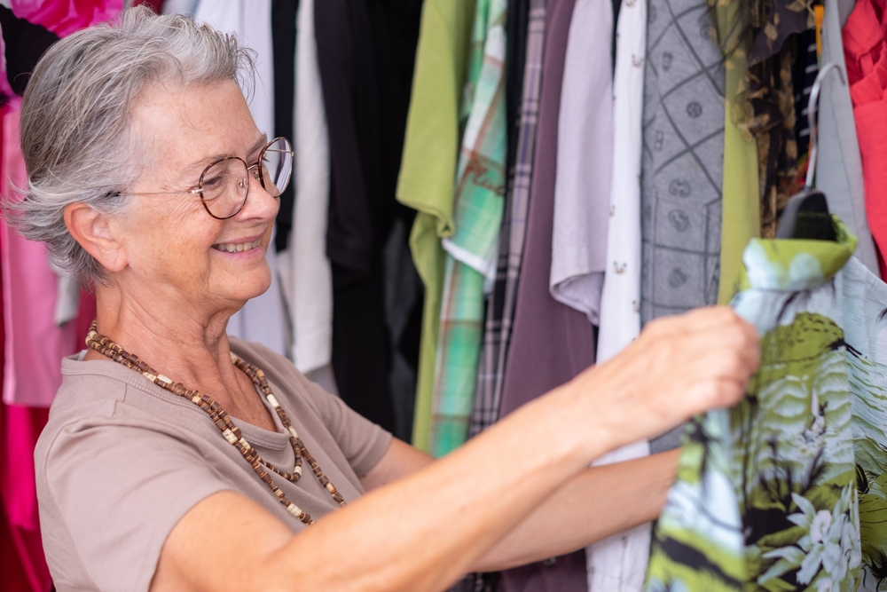 Senior woman looking through shirts to clean out clutter for her madison heights senior apartments