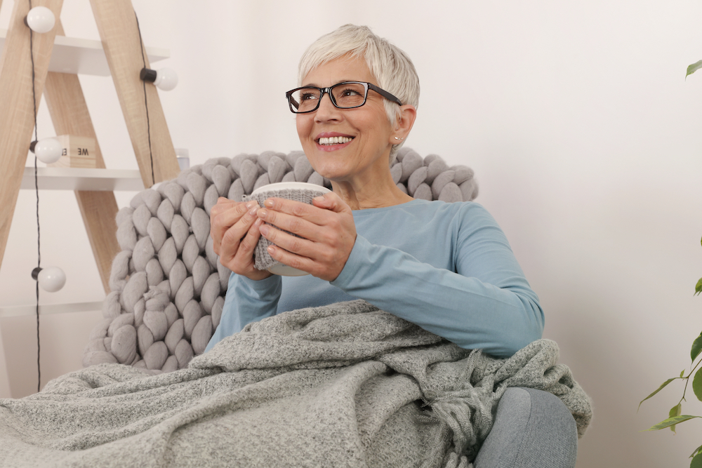 An older woman cozied up with a blanket and tea at senior independent living in Michigan