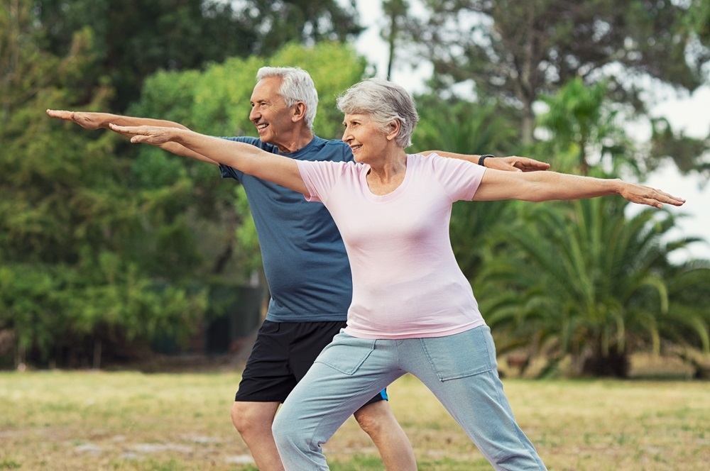 A senior couple practicing yoga outdoors