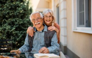 A senior couple hug while sitting on the patio of the Madison Heights senior apartments