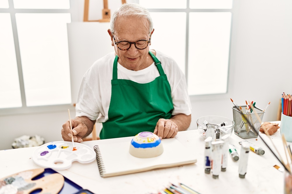 A senior man painting pottery