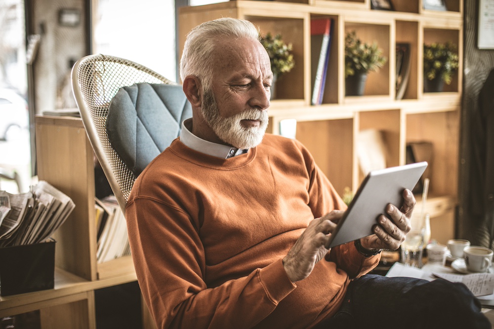 A senior man using a tablet to stay connected to family and friends