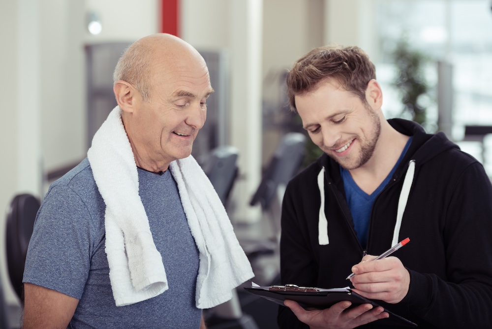 An older adult man working with a personal trainer at the senior independent living in Michigan