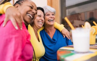 Three senior women enjoy drinks outdoors