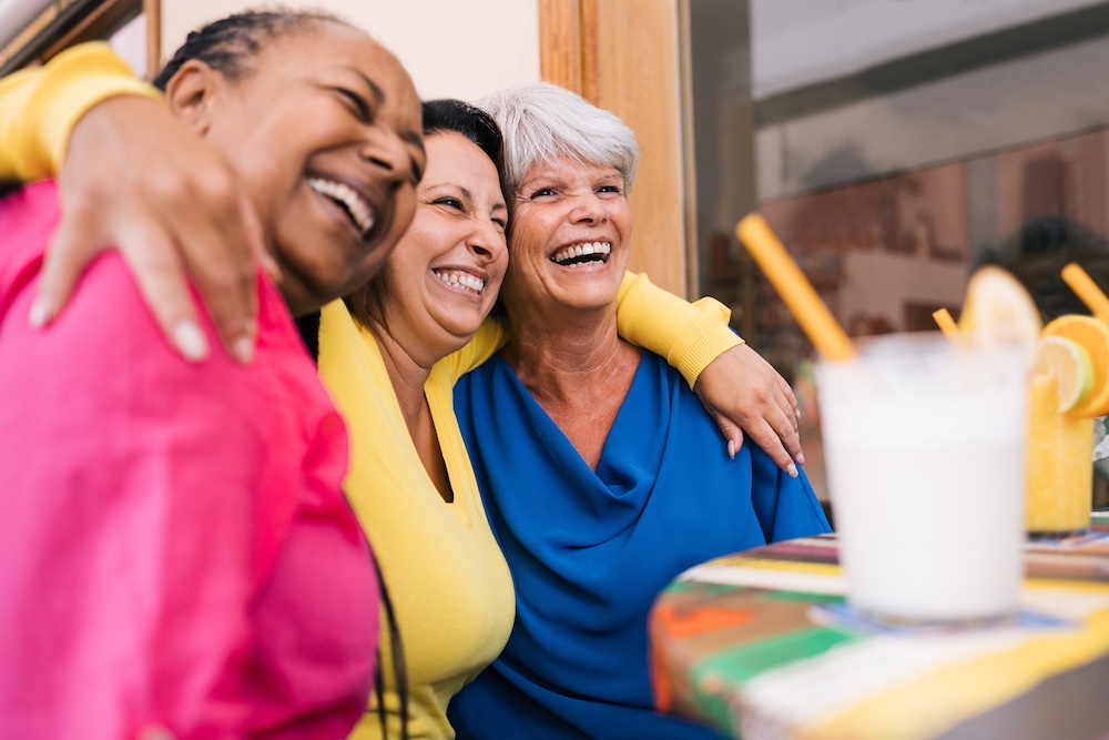 Three senior women enjoy drinks outdoors