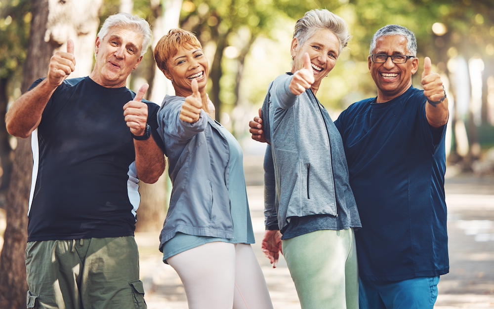 Four active seniors giving a thumbs up, showing their approval of our senior independent living in Michigan