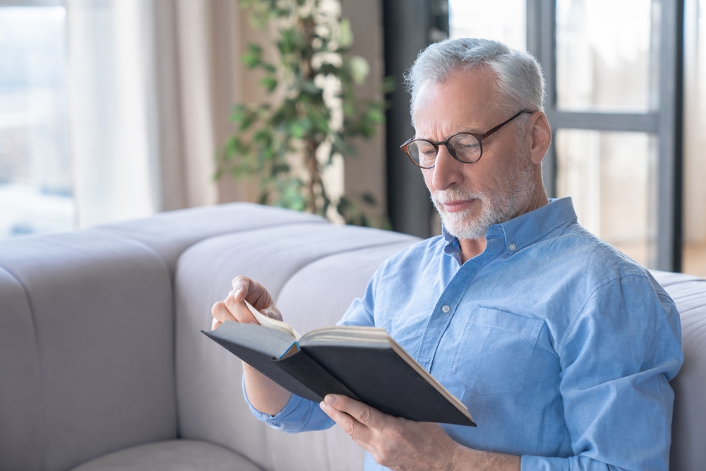 Senior man reading in independent senior living near Madison Heights.