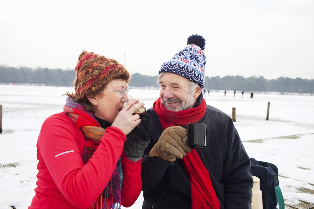 Couple outside of their independent living communities near Royal Oak, MI in winter enjoying a hot drink