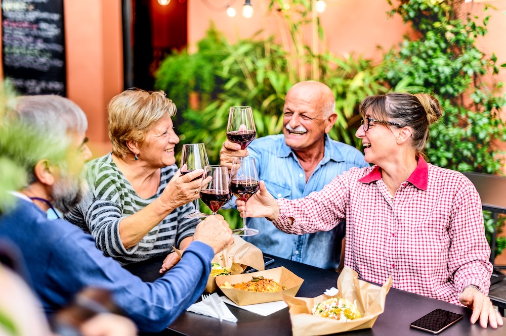 Senior friends outside enjoying a meal and wine together at their independent senior living Michigan